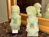 two jade statues sitting on a table in front of a mirror