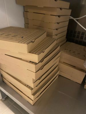 Plusieurs boîtes de pizza sont empilées les unes sur les autres dans une cuisine.