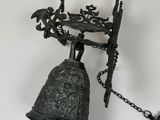 a metal bell hanging from a chain with a bird on it