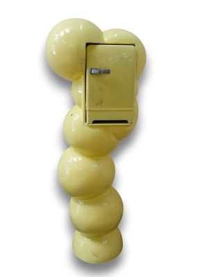 une boîte aux lettres jaune fixée au mur, à laquelle sont accrochés plusieurs ballons
