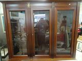 un grand meuble en bois avec des portes en verre dans une pièce