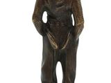 statue of a man with a hat and a cane standing on a wooden base