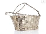 a wicker basket with a handle on a white surface