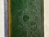 un vieux livre vert posé sur une table blanche
