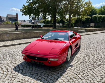 une voiture de sport rouge garée dans une rue pavée