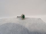 un gros plan d'une bague ornée d'une pierre verte sur un fond blanc