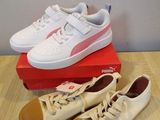 des baskets Puma blanches et roses posées sur une boîte, elle-même posée sur une table en bois