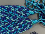 blue and green crocheted scarf with a knot on top of it