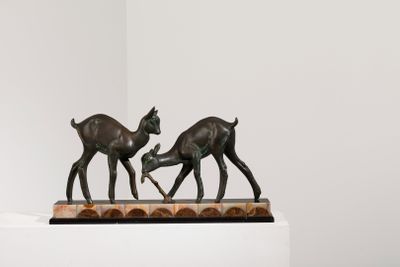 sculpture représentant deux cerfs sur un socle, dans une pièce blanche