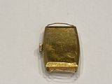 a small gold square shaped object on a white surface