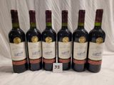 six bottles of wine are lined up in a row on a table