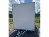 a white trailer parked in a gravel lot with a sky background