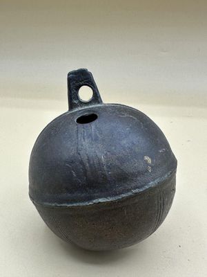 un objet noir posé sur une surface blanche et percé d'un trou