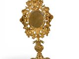 a gold mirror on a stand with a bird on it