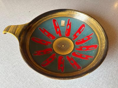 une horloge rouge et verte posée sur une table blanche