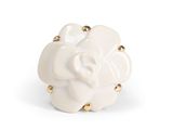 white ceramic flower with gold studs on a white background