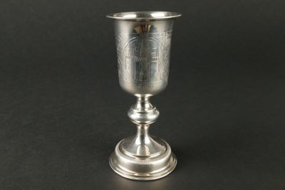 gobelet en argent posé sur une surface noire, avec un fond noir