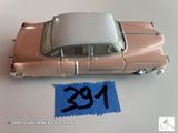 une petite voiture rose avec une étiquette bleue dessus