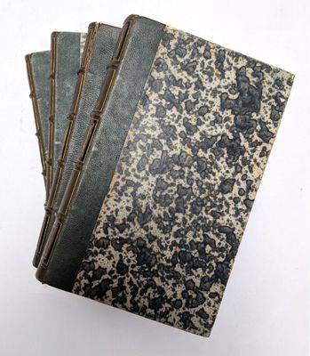 trois vieux livres sont empilés sur une surface blanche