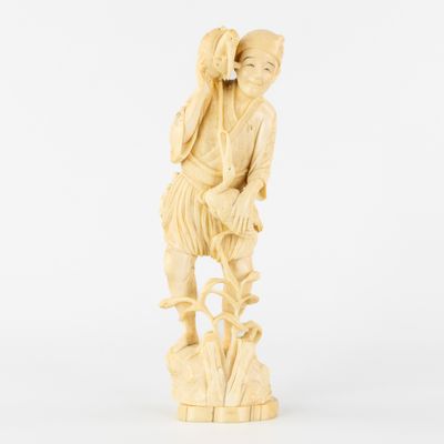 une figurine en ivoire sculptée représentant un garçon assis sur un rocher