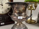 a silver vase sitting on a table next to a clock