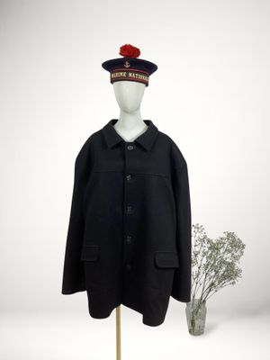 black coat with a red pom pom on top of a mannequin head