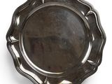 a silver plate with a scalloped edge on a white surface