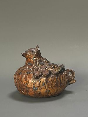 a brown vase with a bird sitting on top of it