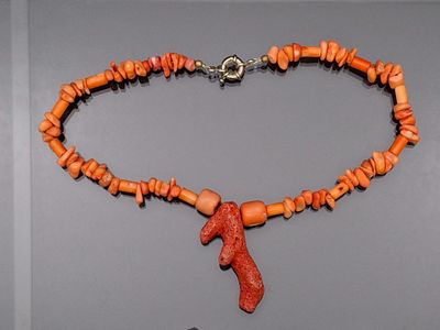 collier composé de perles de corail orange avec un fermoir en argent sur fond gris