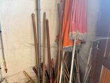 a pile of brooms and rakes next to a wall