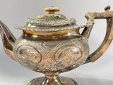 a silver tea pot on a stand with a handle