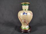 a vase with a bird on it sitting on a stand