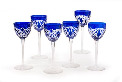 six blue wine glasses are lined up in a row on a white surface