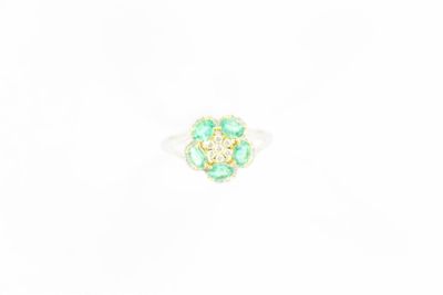un gros plan d'une bague en forme de fleur verte posée sur une surface blanche