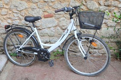 a bicycle parked next to a stone wall with a basket on the back