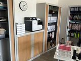 a room with a desk, shelves, and a clock on the wall