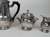 three pieces of silverware sitting on top of a white table