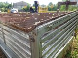 a man standing next to a metal fence that has rust on it