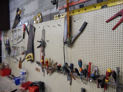 de nombreux outils accrochés à un panneau perforé fixé au mur