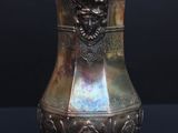 a silver vase sitting on a table with a black background