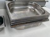 several stainless steel pans are lined up on a white counter