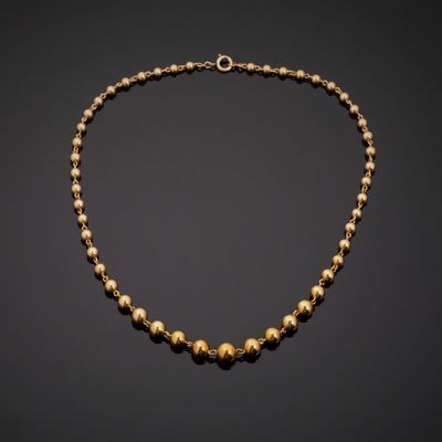 a gold beaded necklace on a black background