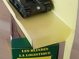 un petit char de jouet posé sur une boîte, elle-même posée sur une table