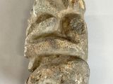 a stone sculpture of a face on a white surface