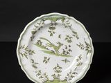 a green and white plate with birds and flowers on it