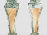 une paire de vases en marbre vert reposant sur un socle en bois, sur fond blanc