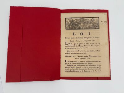 un livre ouvert à couverture rouge posé sur une table blanche