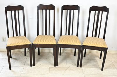 quatre chaises en bois avec des assises rembourrées jaunes dans une pièce