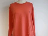 an orange sweater on a mannequin stand against a white wall