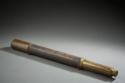 un vieux télescope en laiton dans un coffret en bois, posé sur une surface grise